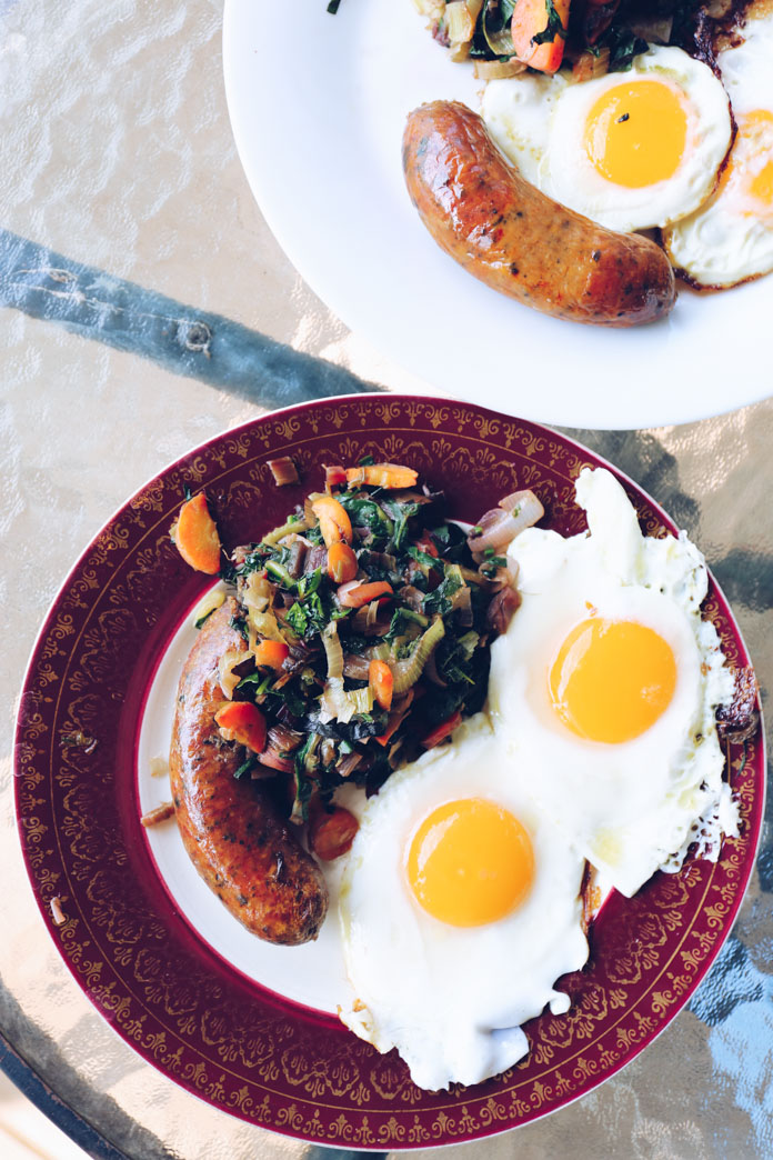 Pan-fried eggs, lamb sausages and sauteed farm grown greens